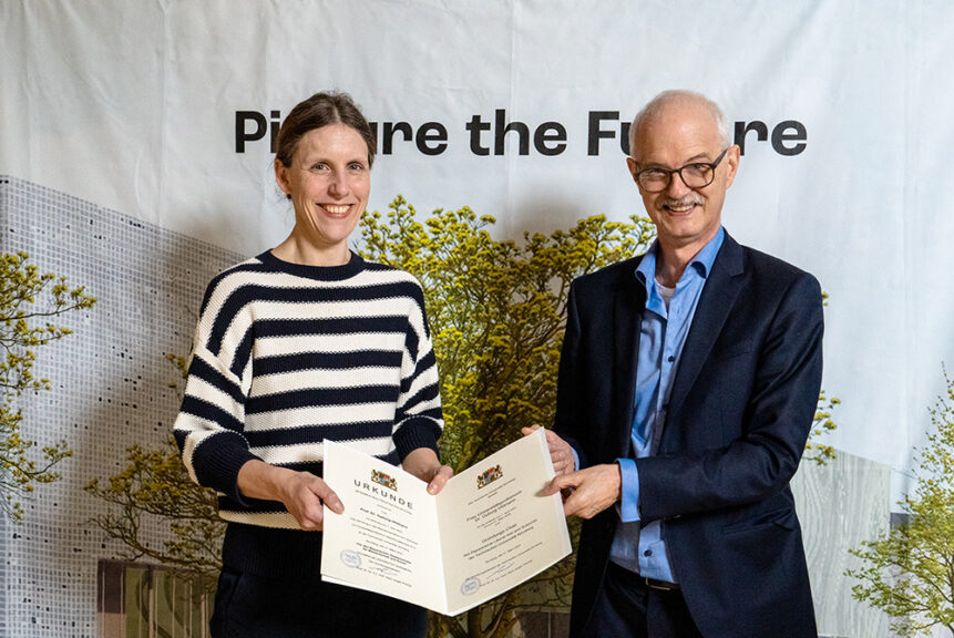 Prof. Prömel und Prof. Uhlmann halten gemeinsam die aufgeschlagene Urkunde hoch. Sie stehen vor einer Pressewand, auf die "Picture the Future" geschrieben ist.