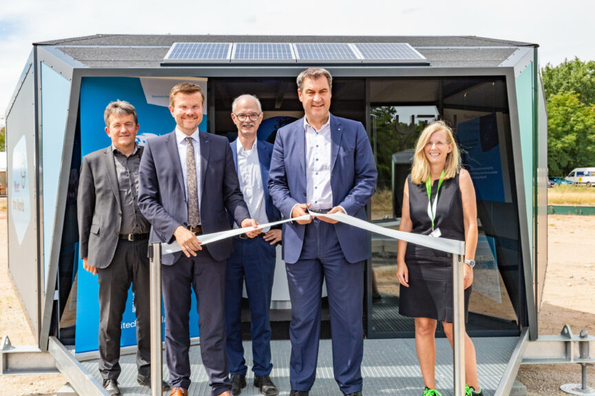 Die Rednerinnen und Redner stehen vor einem der Experience Cubes. Dr. Markus Söder hält eine Schere in der Hand und durschneidet ein Band.