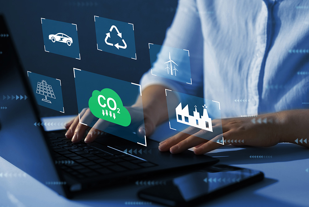 Ein Mann tippt auf einem Laptop, im Vordergrund erscheinen Symbolbilder, beispielsweise für E-Autos, Recycling oder erneuerbare Energien.