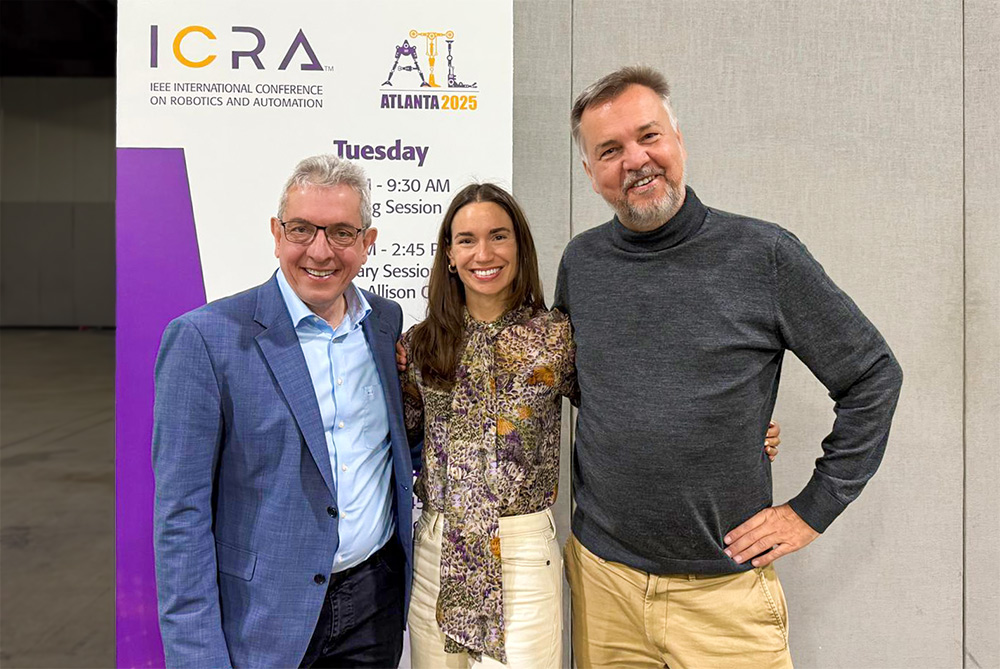 Three conference participants smile in front of an ICRA 2025 Atlanta banner at the IEEE International Conference on Robotics and Automation.