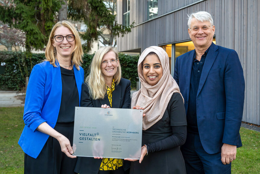 Vier Mitarbeitende der UTN stehen vor einem Gebäude und halten gemeinsam eine Zertifikatsplakette für das erfolgreich bestandene Diversity-Audit