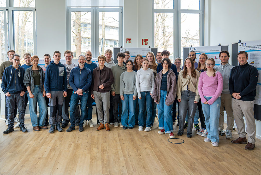 Gruppenfoto der Hochbegabtenklasse des Albrecht-Dürer-Gymnasiums Nürnberg bei einem Besuch in einem Hochschulgebäude vor wissenschaftlichen Postern.