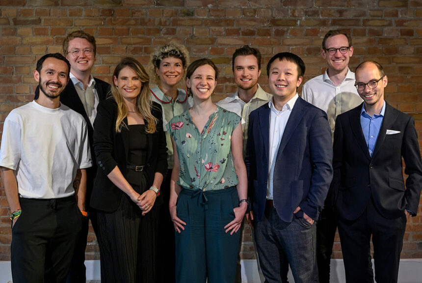 Neue Mitglieder der Jungen Akademie stehen gemeinsam mit Professor Yuki Asano lächelnd vor einer Backsteinwand.