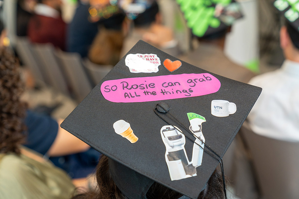 Decorated graduation cap featuring the text “So Rosie can grab ALL the things” and motifs from robotics and UTN.