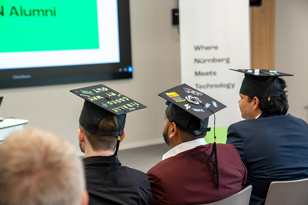 Three graduates wear individually decorated doctoral caps at the 2026 UTN Graduation Ceremony.